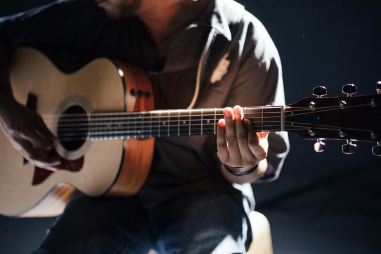 An image showcasing a skilled guitarist gently pulling on a newly installed guitar string, highlighting the intricate details of their fingers and the tautness of the string, emphasizing the importance of stretching for optimal performance